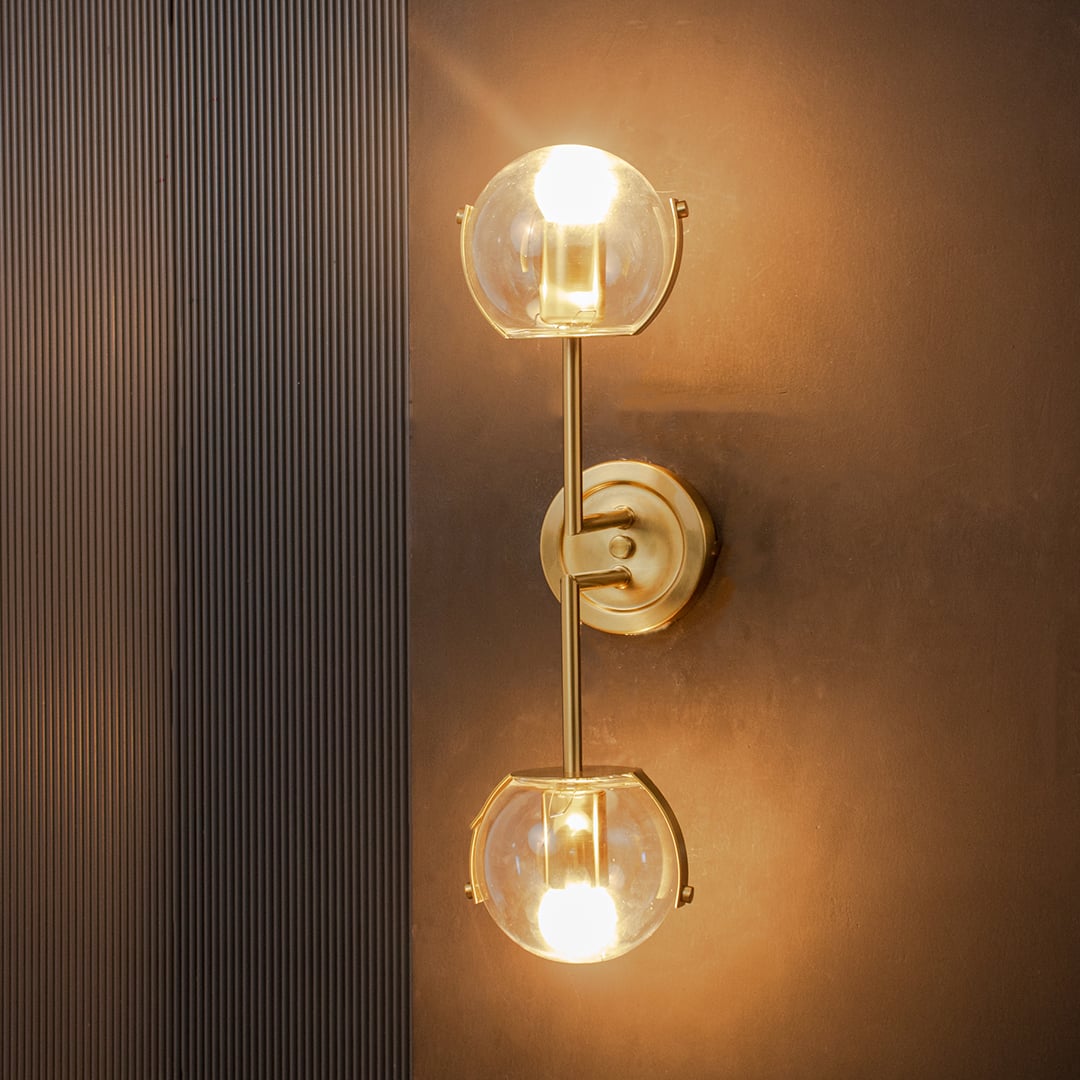 Wall lamp glowing with double clear glass globes and gold finish frame creating warm ambient illumination for modern interiors.