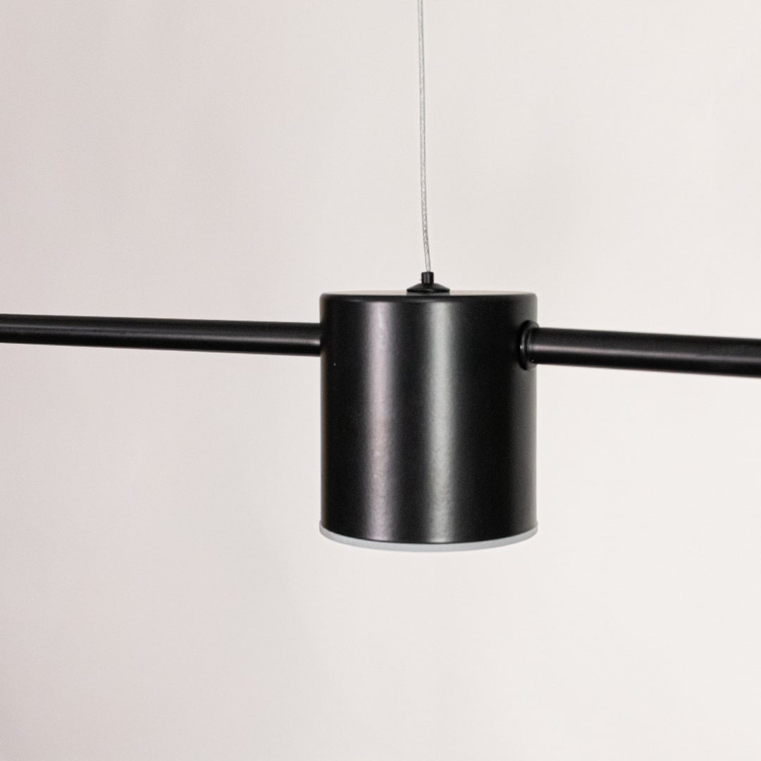 Closeup view of linear pendant light showcasing cylindrical light heads metal finish and clean modern detailing.