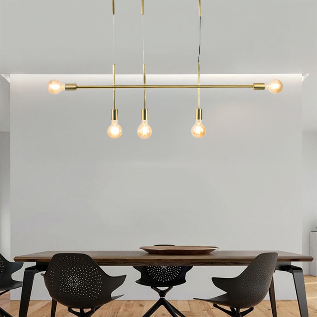 Gold metal linear chandelier with exposed globe bulbs styled in a modern interior adding warm ambient lighting to the space.