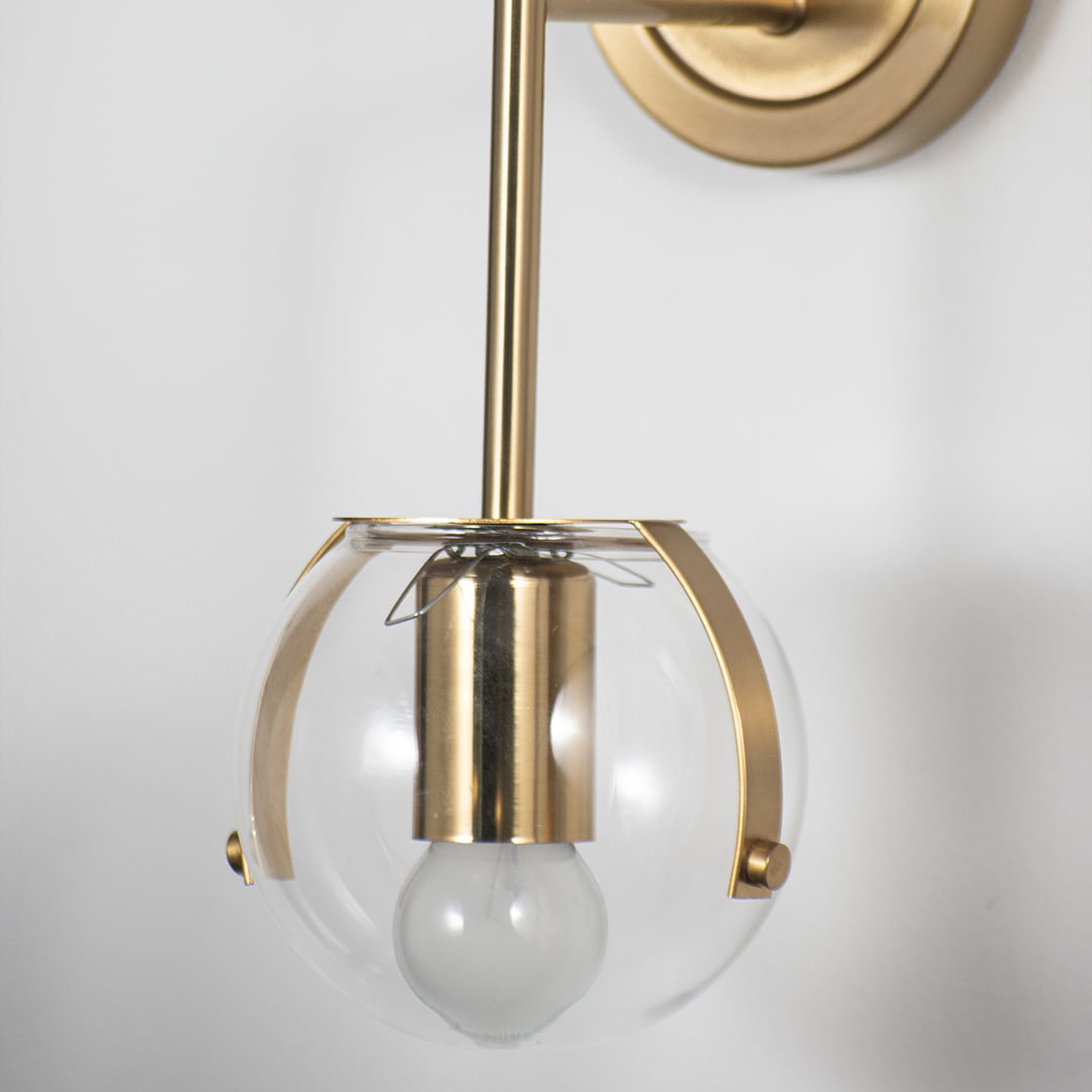 Closeup of wall lamp with double clear glass globes and sleek gold metal frame showcasing elegant decorative wall lighting design.
