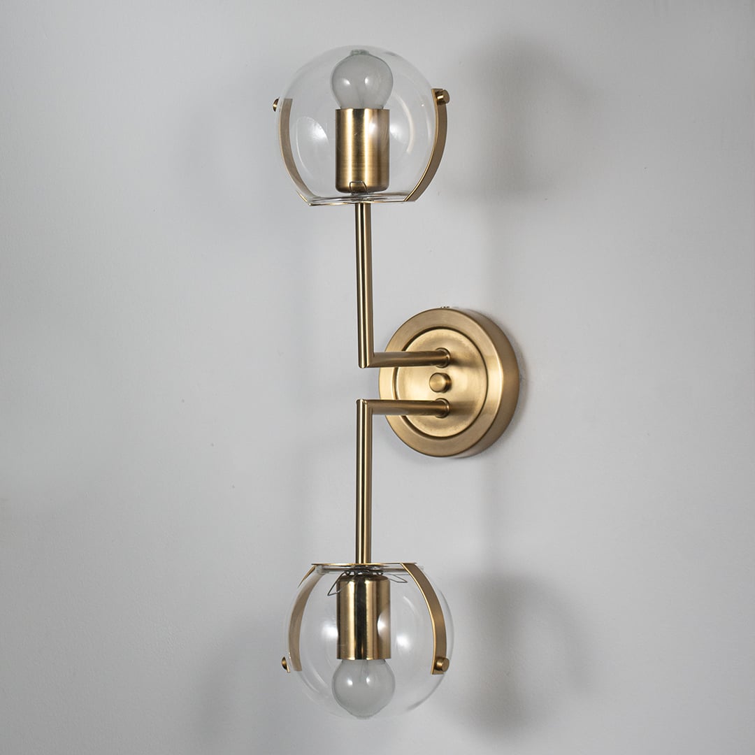 Wall sconce with double clear glass globes and gold finish frame perfect for bedroom living room and luxury modern interiors.