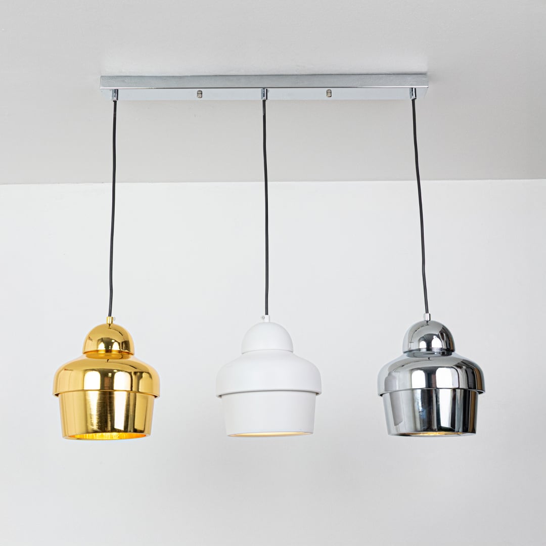 Metal pendant lights in gold white and chrome shown against a white background with bulbs on showcasing their glossy finish and clean minimal profile.