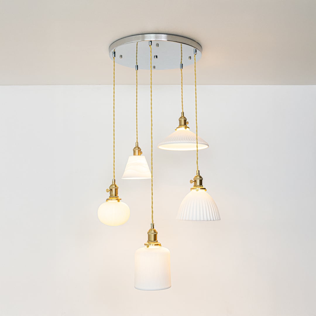Soft glowing ceramic pendant cluster with white textured shades and gold fittings displayed on a bright white background for decor inspiration.