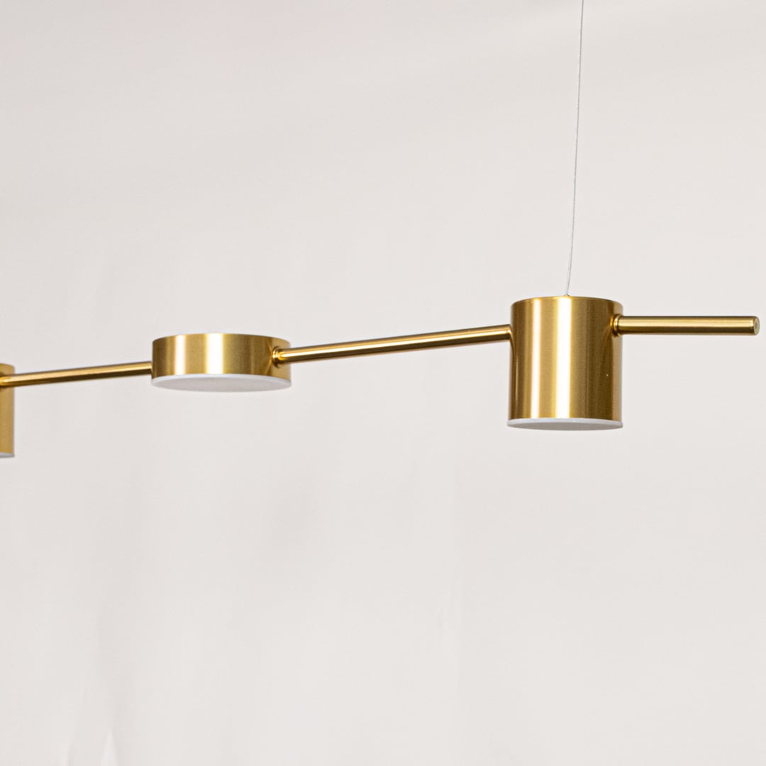Detailed closeup of the gold linear pendant light focusing on its cylindrical light head and brushed metallic texture for a premium modern aesthetic.