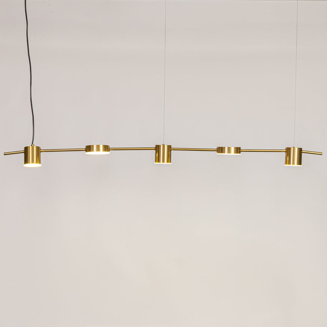 Gold linear pendant light displayed against a clean white background with lights on showcasing its warm glow and minimal modern style.