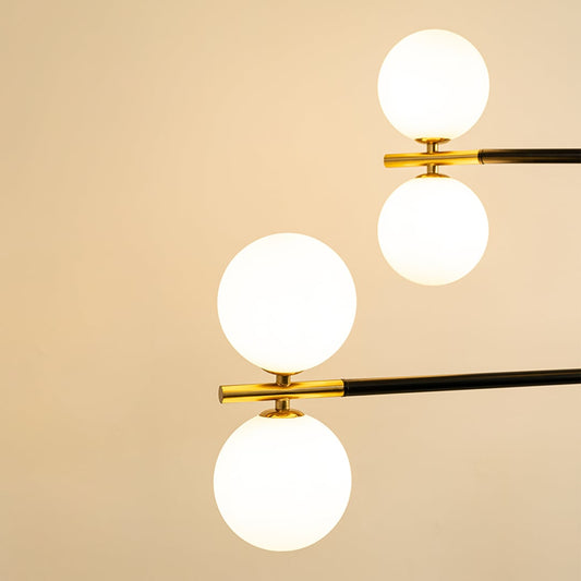 Close view of black and gold chandelier showing frosted white glass globes lights on metallic detailing and precise geometric craftsmanship.