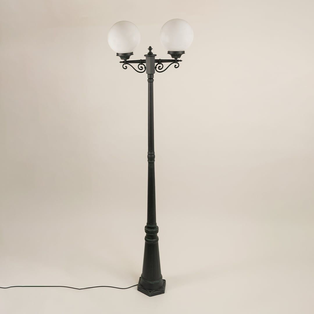Double-globe outdoor lamp post shown on a white background with both lights turned off revealing the matte black pole structure and smooth round globes clearly.