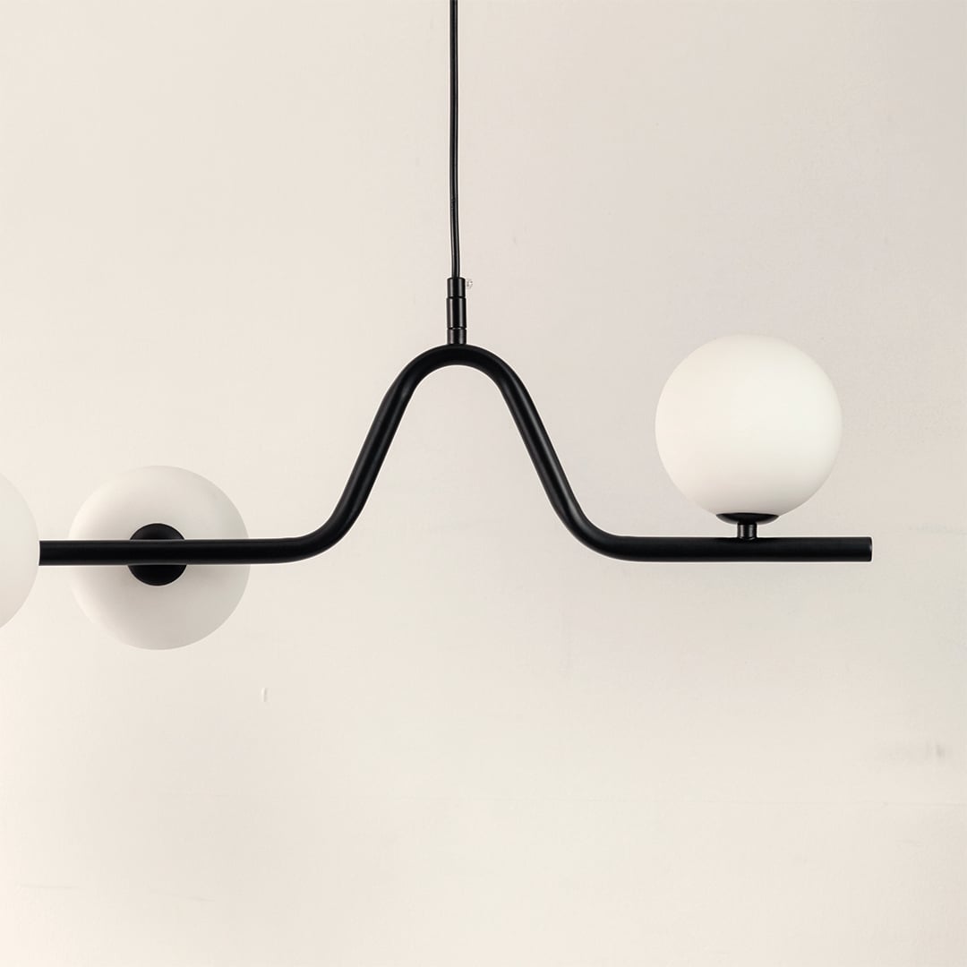 Closeup of black metal chandelier showing curved frame frosted globes and refined contemporary craftsmanship.
