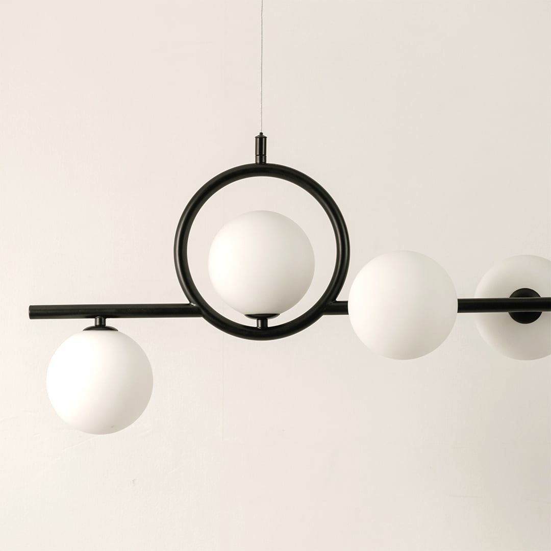 Closeup view of black metal chandelier showing smooth matte finish circular accents and frosted glass spheres.