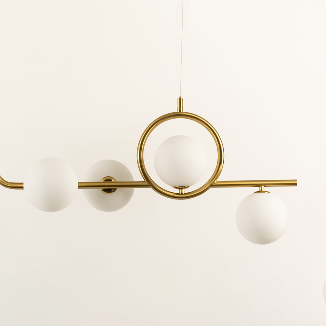 Closeup view of gold circular accent chandelier with white globe shades in a front view against a plain background with lights off ideal for artistic lighting décor.