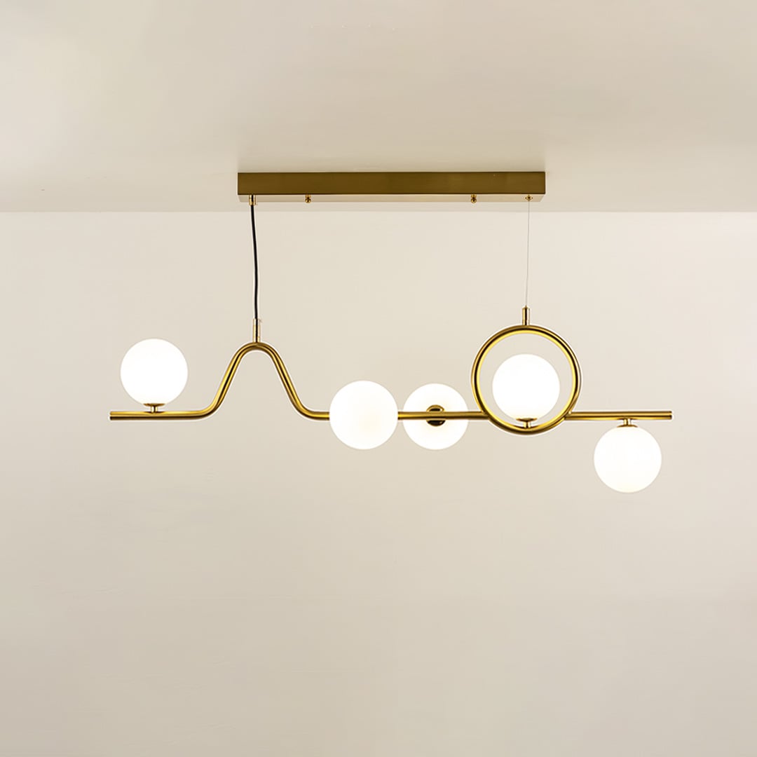 Gold chandelier with circular accent and globe lights in a front view against a plain ceiling background with lights on ideal for artistic décor styling.