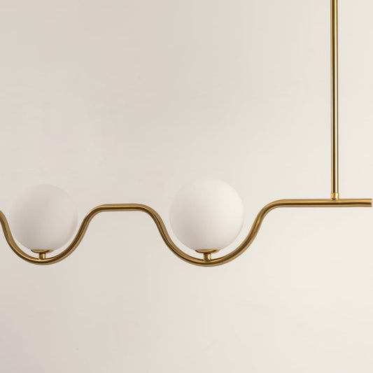 Closeup of gold linear chandelier showing frosted glass globes sleek metallic frame and focused spotlight detailing.