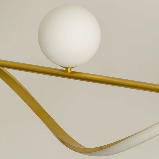 Closeup view of gold metal wave chandelier showing smooth curved frame and matte white globes for modern home lighting.