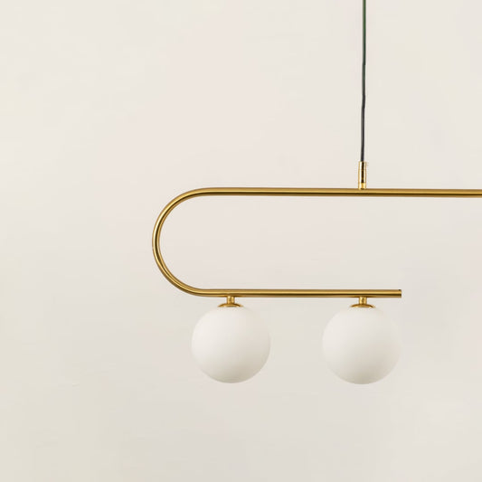 Closeup view of gold asymmetrical ceiling light with curved arm and white globes in a front view against a plain white background with lights off perfect for luxury lighting décor.