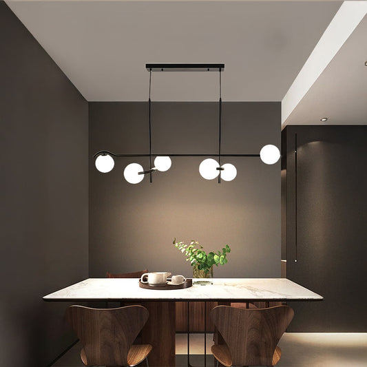Black metal chandelier with soft white globes styled in a modern living space creating warm elegant ceiling lighting decor.