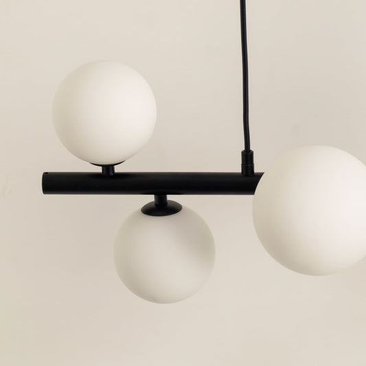 Closeup of black metal chandelier showing smooth matte frame frosted globes and contemporary artistic detailing.