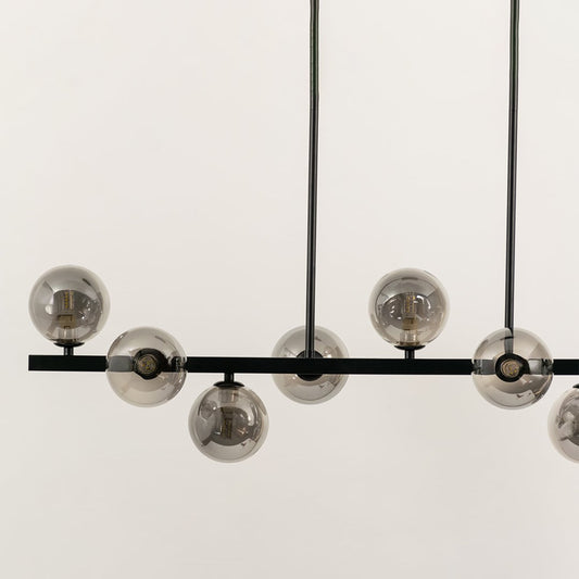 Closeup view of black multi arm chandelier with smoky globe bulbs in a front view against a white background with lights on perfect for bold contemporary lighting décor.