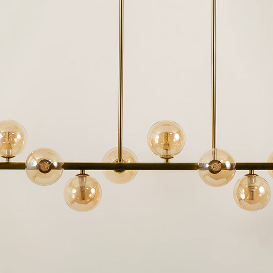 Closeup view of gold multi arm chandelier with globe bulbs in a front view against a white background with lights on ideal for luxury ceiling décor and modern interiors.