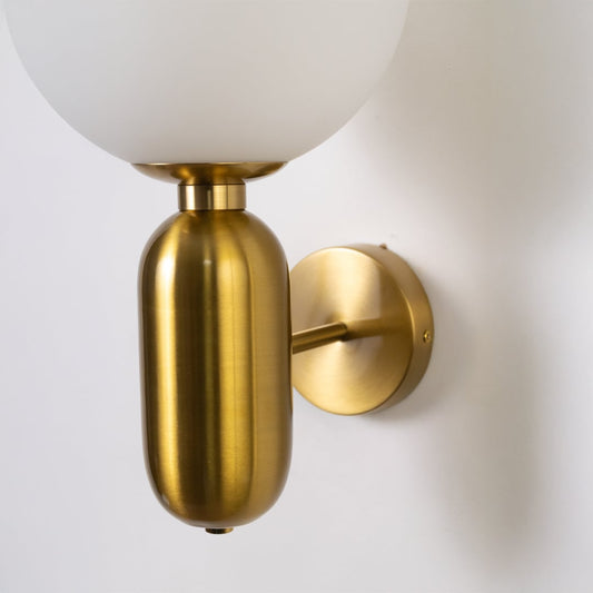 Closeup of brass wall sconce with frosted glass globe shade elegant modern wall light for bedroom dining and living room lighting decor.