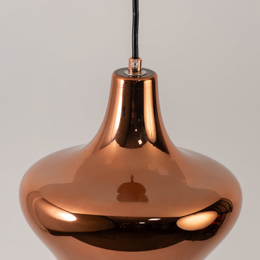 Closeup of copper metal pendant light showing reflective finish elegant curves and warm directional illumination.