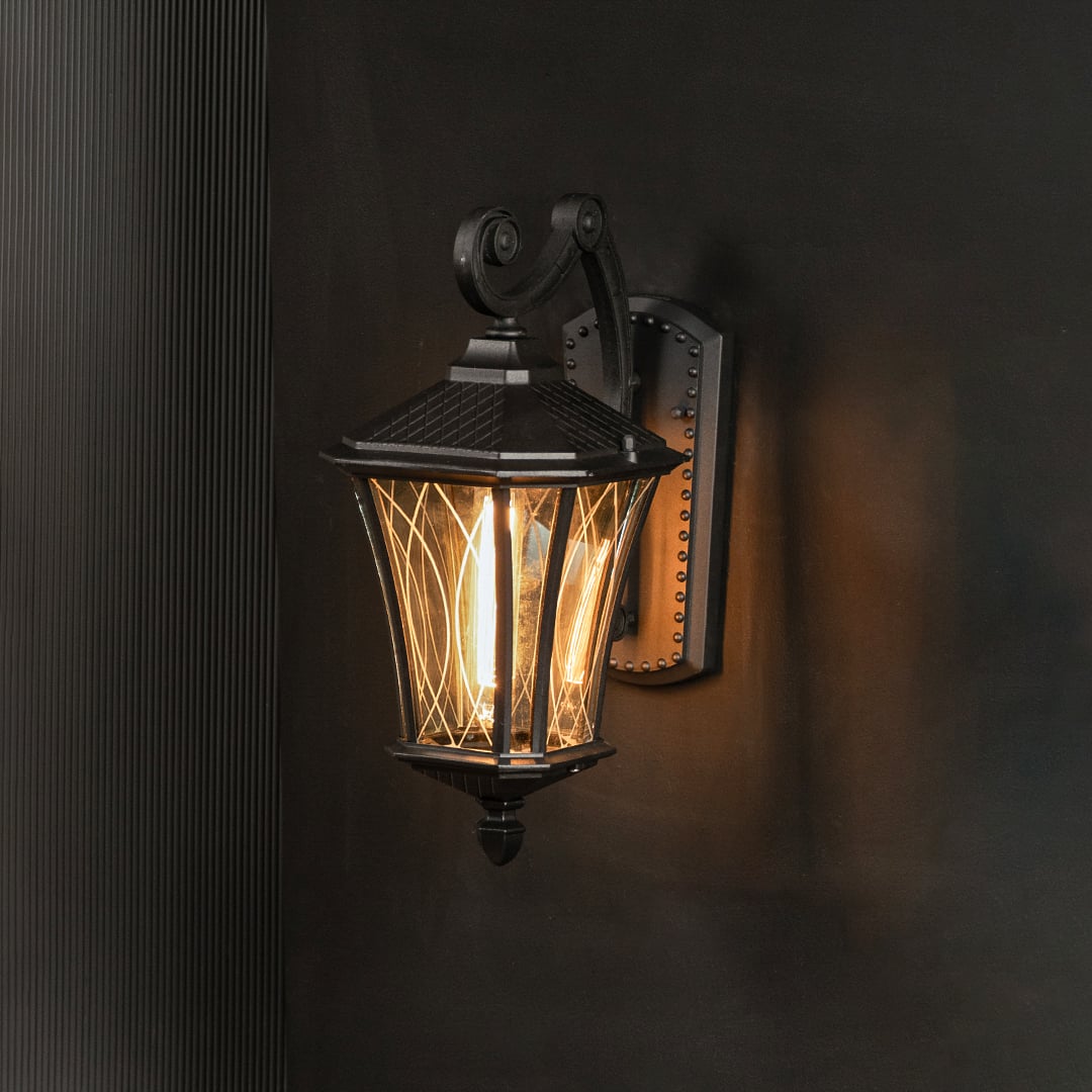 Black outdoor lantern with textured glass displayed with light on against a dark background emphasizing warm illumination and classic outdoor appeal.