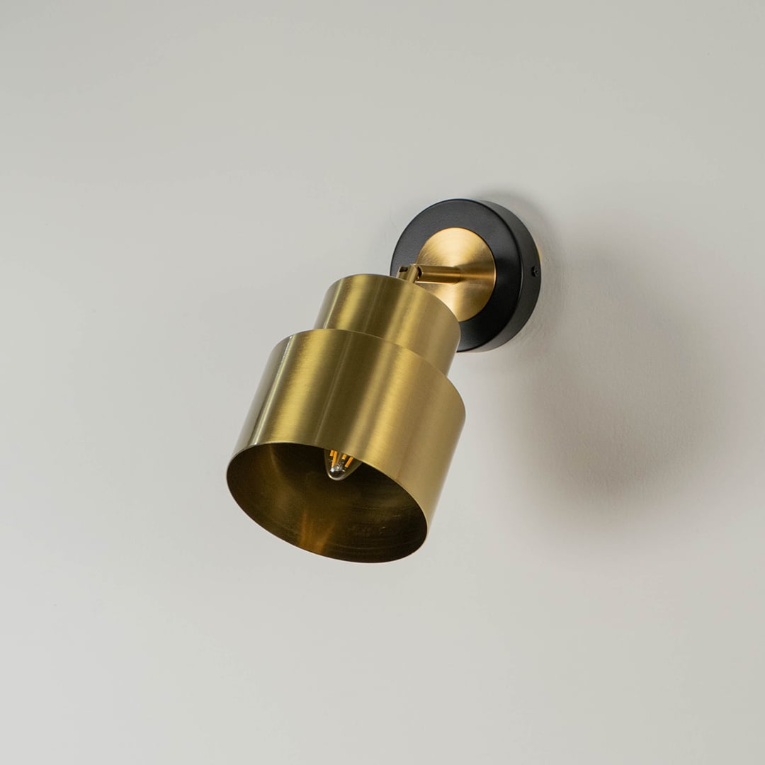 Gold wall light displayed without illumination against a white background showcasing its elegant design and modern layered shade.