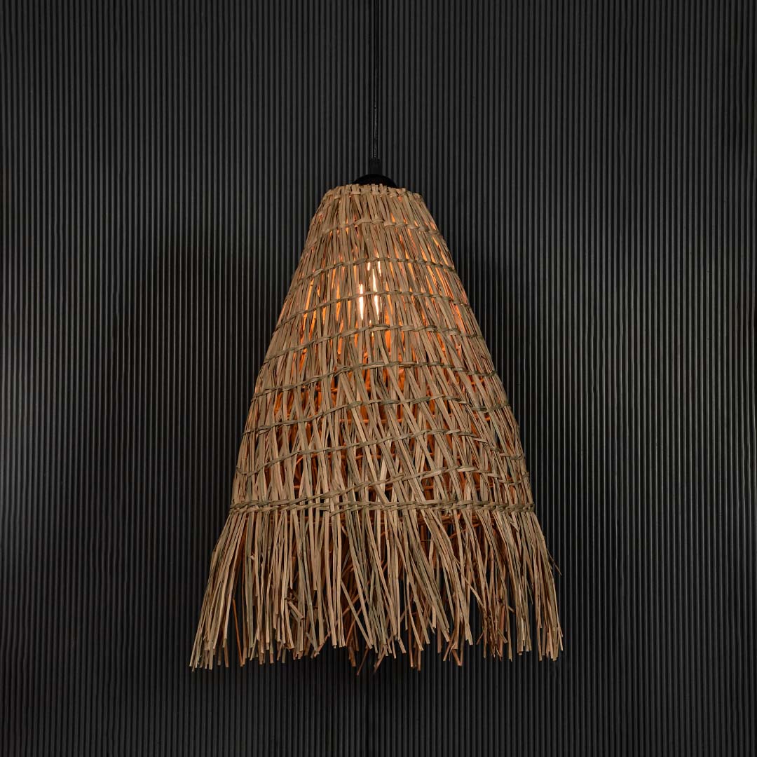 Rattan pendant light with tall woven conical shade and fringe displayed on black background for rustic home decor.