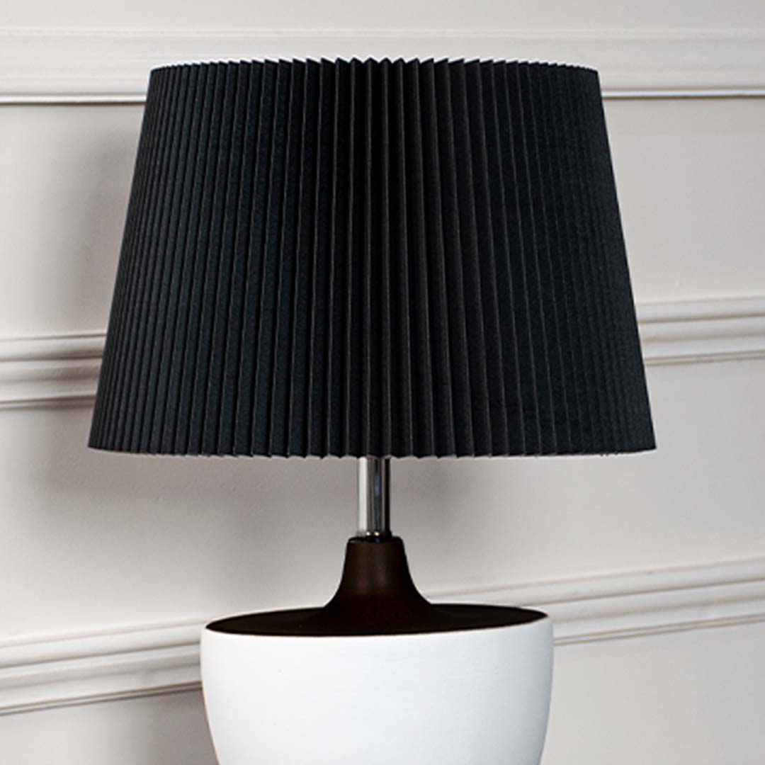 Detailed view of black pleated lampshade and smooth white ceramic base with premium texture finish.