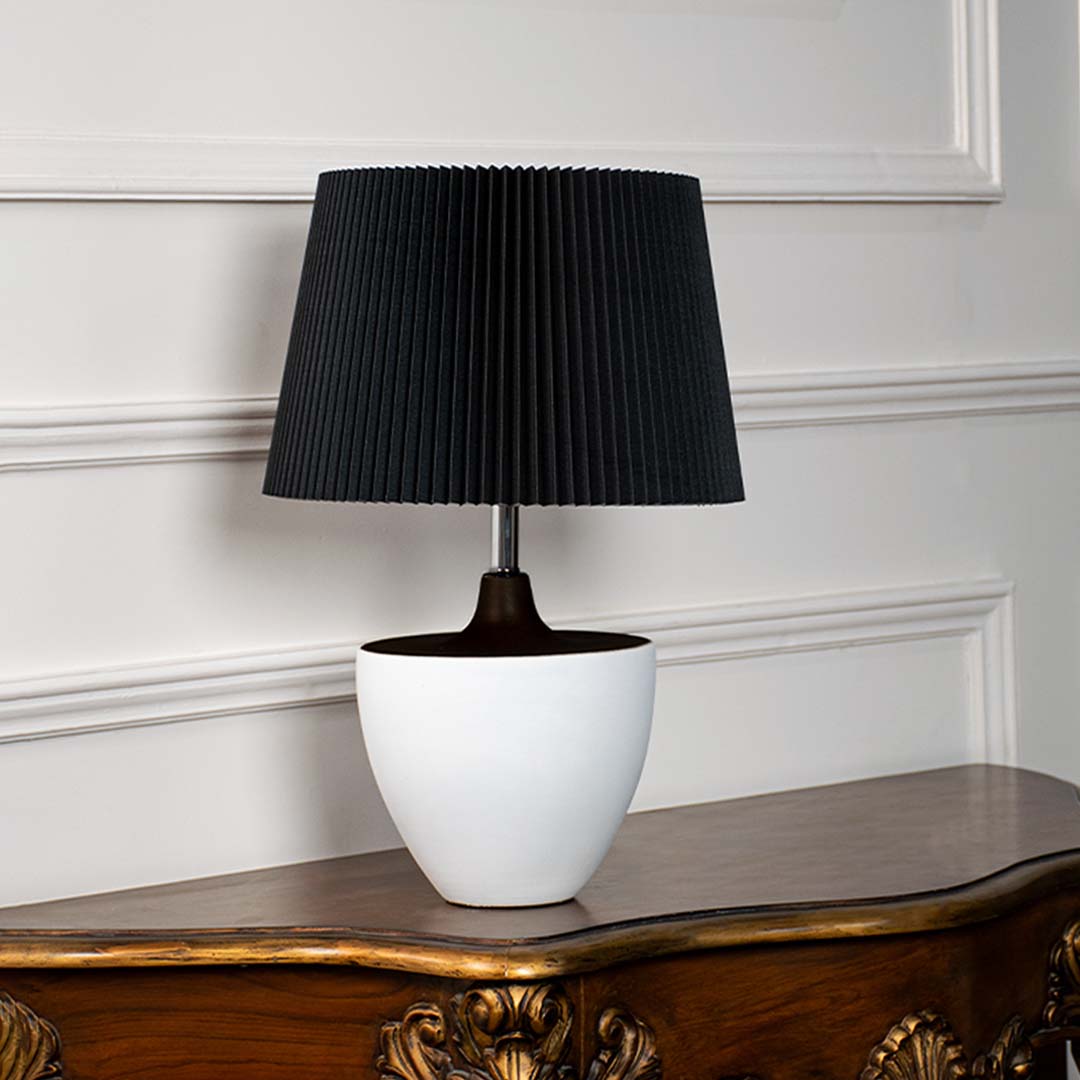Black pleated table lamp turned off displayed on a white background highlighting its elegant form and finish.
