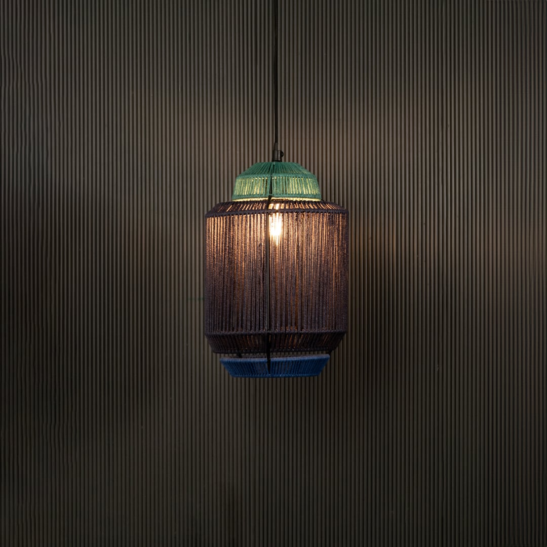 Decorative pendant light with woven shade and green top shown unlit on black background creating textured ambient lighting appeal.