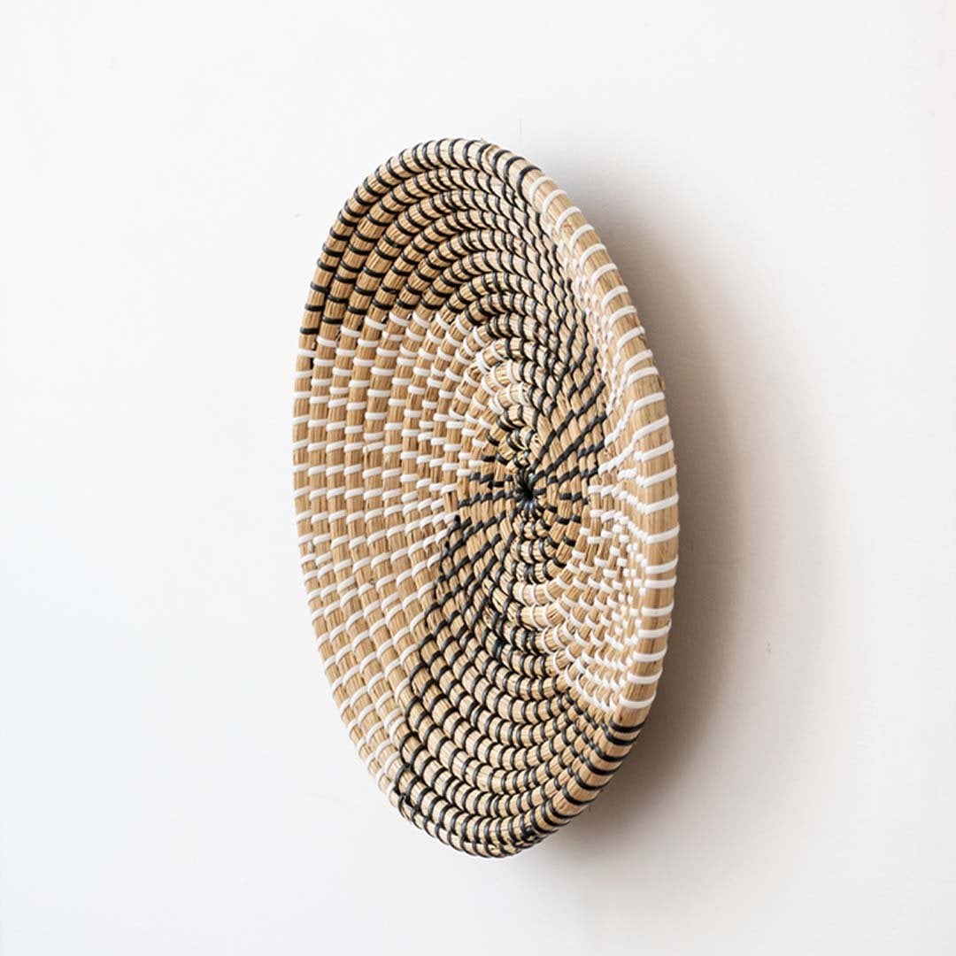 Side view of handwoven wicker basket wall decor showing spiral woven depth and natural texture for boho and rustic interiors.