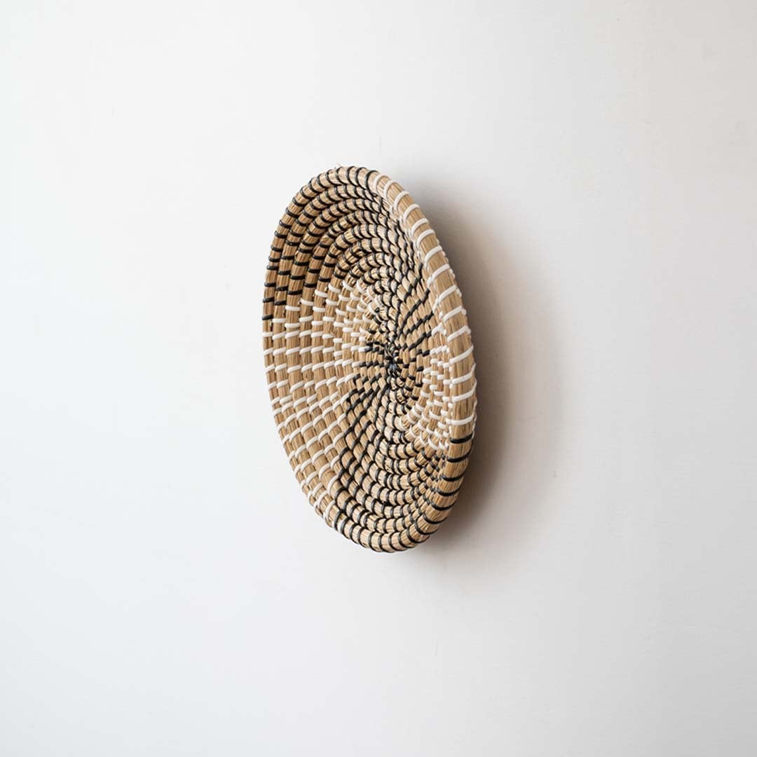 Side view of handwoven wicker basket wall decor showing woven spiral texture and depth for rustic and boho interiors.