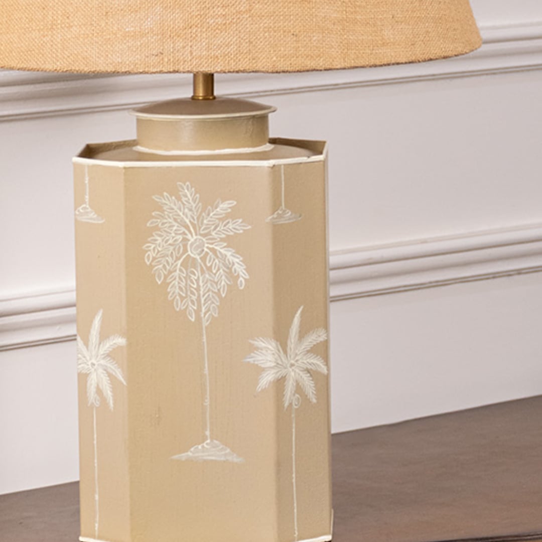 Closeup of palm design table lamp showcasing elegant white palm engravings on smooth beige ceramic base adding tropical charm to contemporary interiors.
