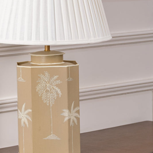 Closeup of beige palm table lamp highlighting detailed palm engraving on smooth ceramic base adding coastal charm to contemporary decor.