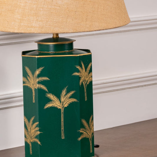 Closeup of green palm table lamp highlighting intricate golden palm pattern on glossy green ceramic base adding tropical sophistication to interior spaces.