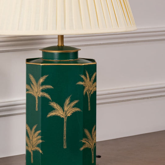 Closeup of green palm table lamp highlighting intricate golden palm detailing on smooth green ceramic base adding tropical luxury to modern home decor.