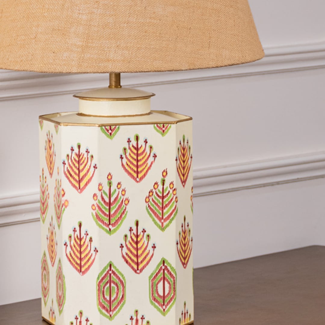 Close view of the ceramic lamp base featuring intricate red and green floral motifs on a cream background. The fine detailing and gold-lined rim reflect artisanal craftsmanship perfect for refined home styling.