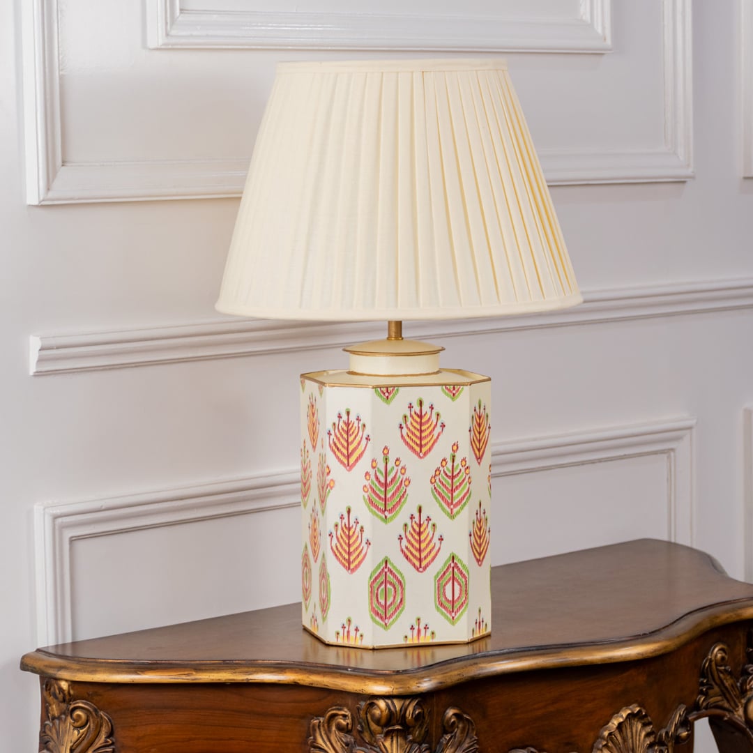 Ivory tribal pattern table lamp turned off displaying detailed geometric tribal artwork in bright hues of orange pink and green on an ivory base paired with a cream pleated shade.