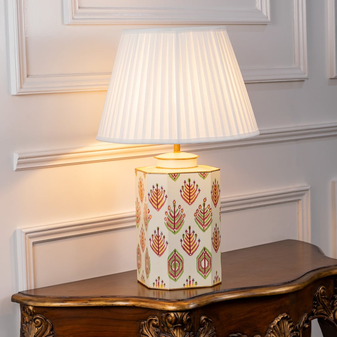 Beautiful ceramic table lamp featuring intricate floral motifs in red and green hues with a pleated white shade glowing softly on a clean white background. The elegant handcrafted design and warm light make it perfect for living rooms bedrooms and modern