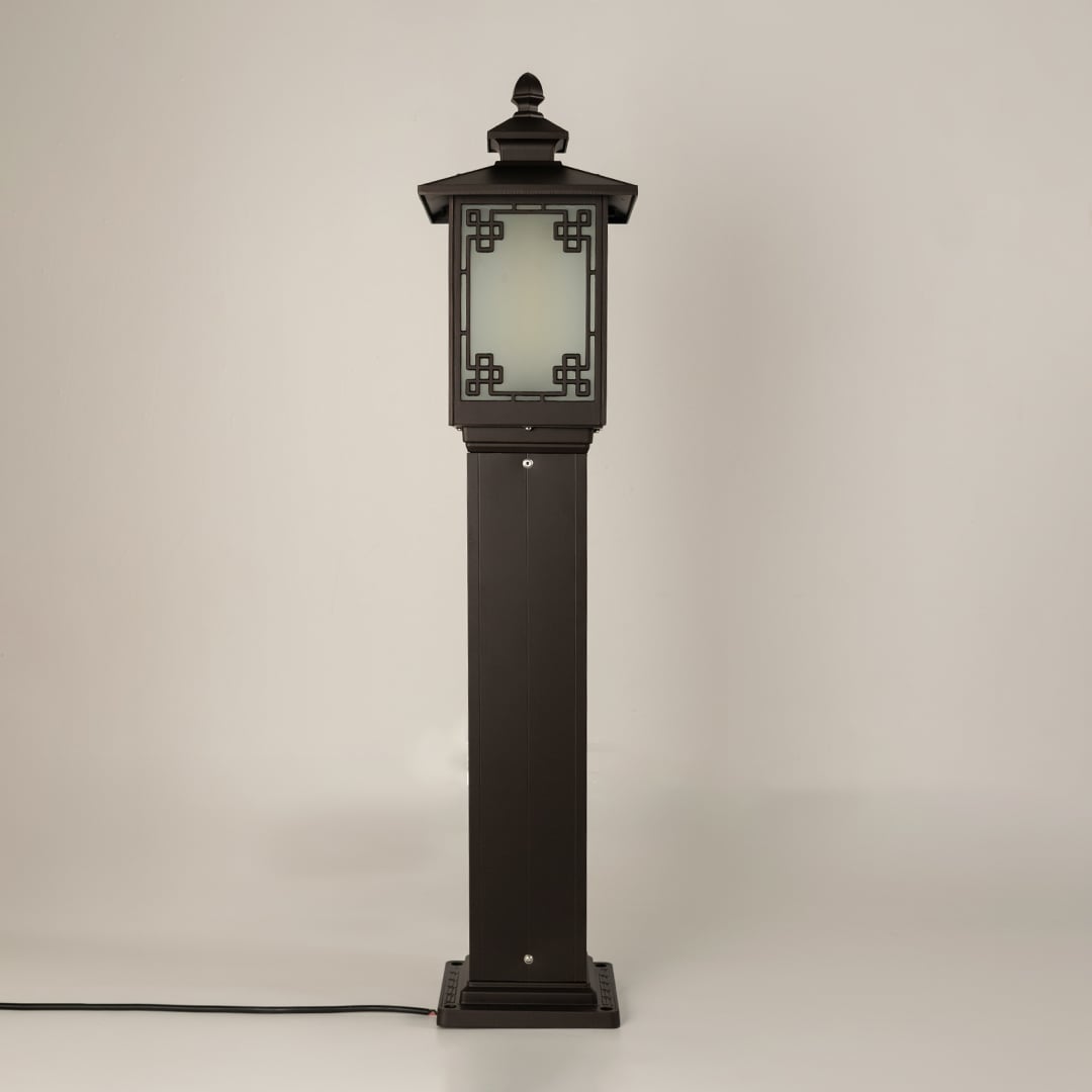 A black outdoor bollard lamp shown on a white background with the light off featuring a tall rectangular post frosted glass panel and decorative metal patterning.