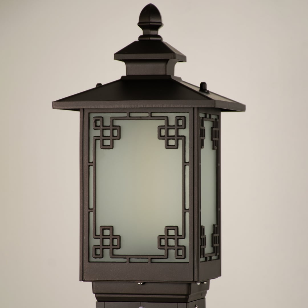 A closeup view of the outdoor lamp head showing the intricate geometric border design around the frosted glass panel with crisp detailing on the dark metal structure.
