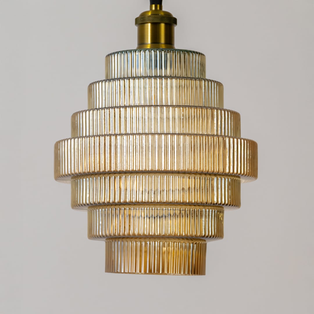 Closeup of the ribbed tiered glass pendant light showing detailed texture layered structure and warm illuminated glow.