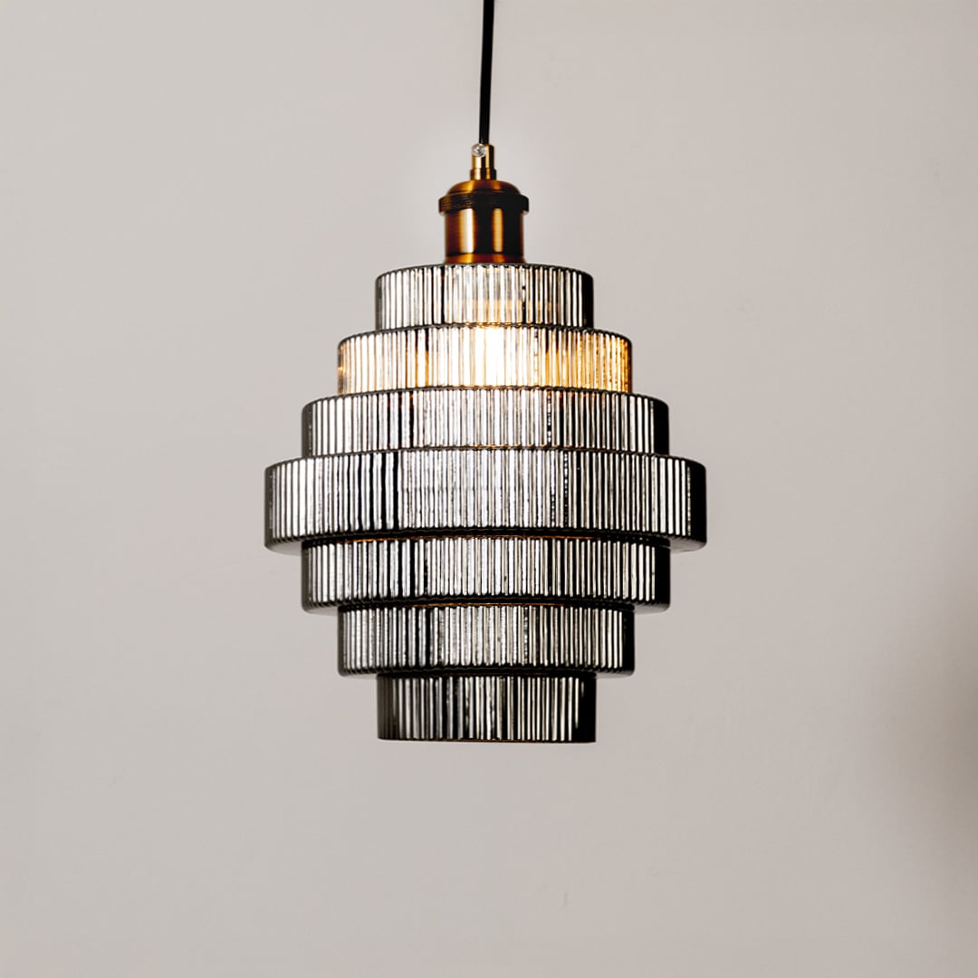 Pendant light with tiered ribbed glass shade glowing on a clean white background highlighting its layered modern structure and warm illumination.