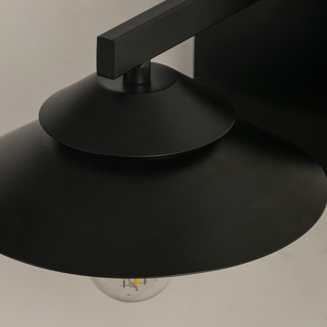 Close detailed view of the black wall light showing the layered shade metal finish and visible bulb for a clean contemporary lighting look.