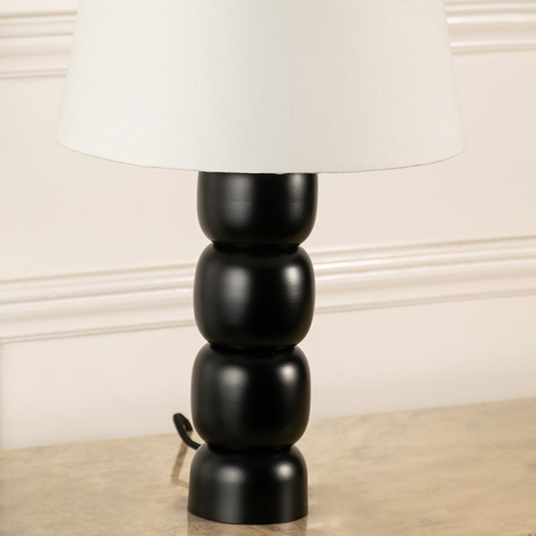 Closeup of black table lamp base with sculpted stacked form showing smooth finish solid build and refined modern Decor detail.