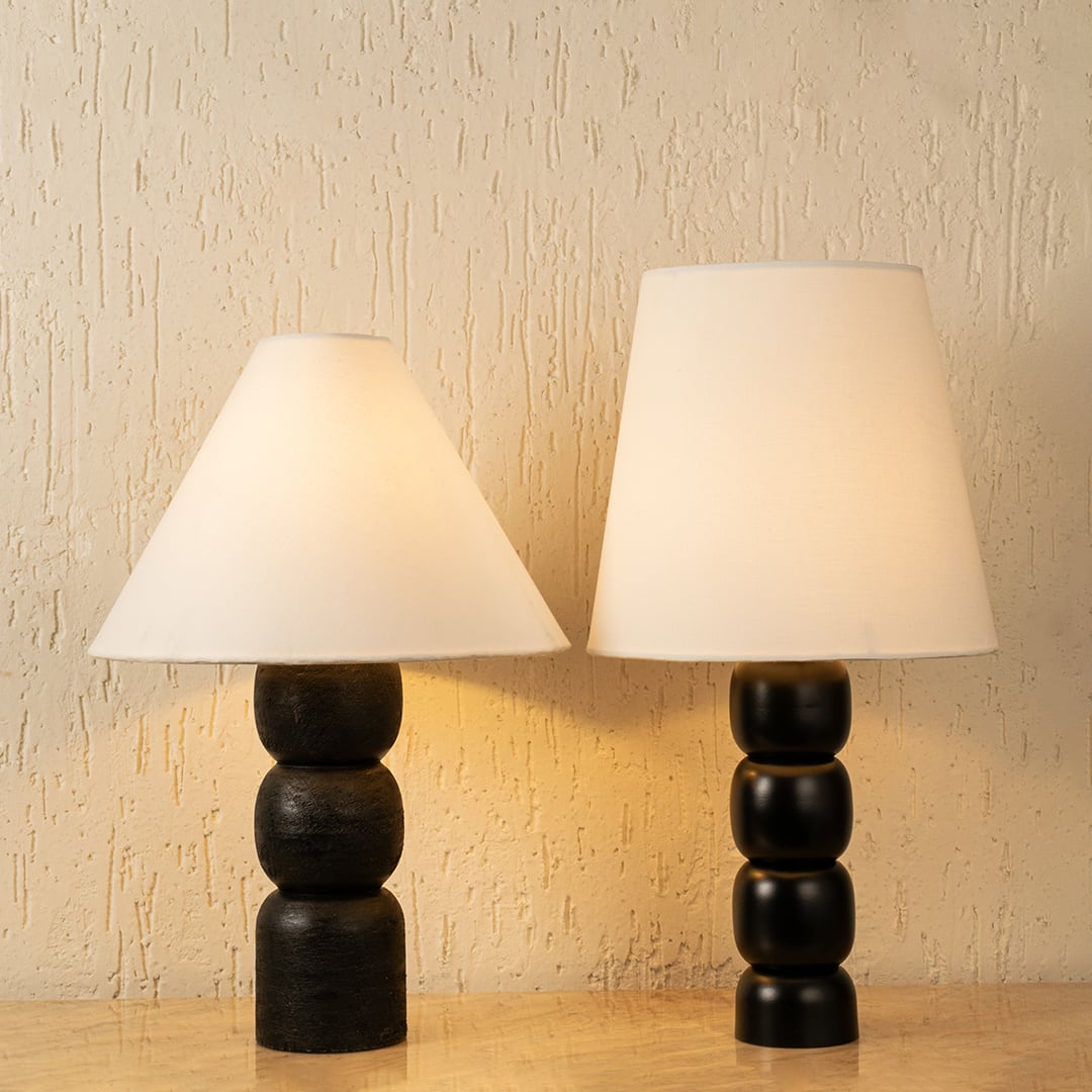 Pair of black metal table lamps with fabric shades placed on wooden surface for warm ambient room lighting Lifestyle Image.