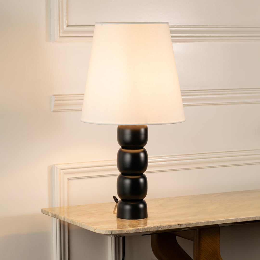 Stylish table lamp with sculpted black metal base and white shade displayed on console table for modern luxury home decor lighting.