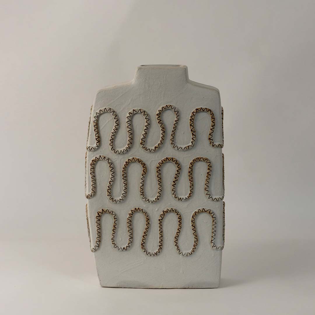 Tall white ceramic vase with artistic zigzag carved design styled for modern living room and office interior decoration.