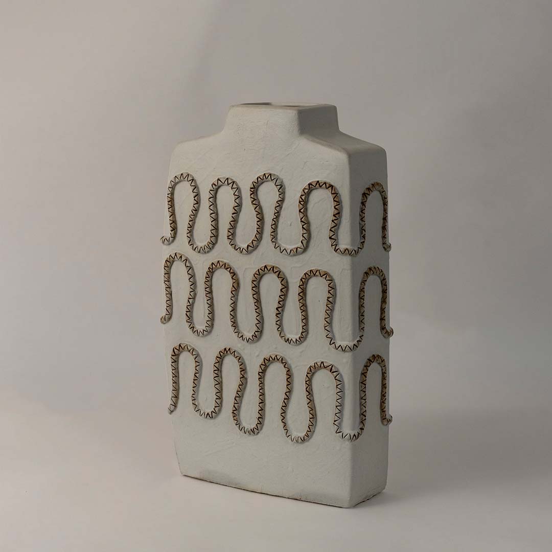 Side angle view of tall white ceramic vase with zigzag carved textured design perfect for modern shelf and living room decor.