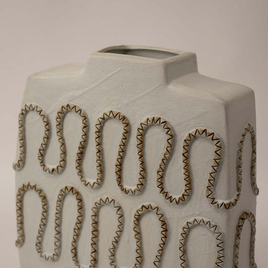 Closeup of handcrafted white ceramic vase with detailed zigzag textured carving highlighting artistic craftsmanship for interiors.